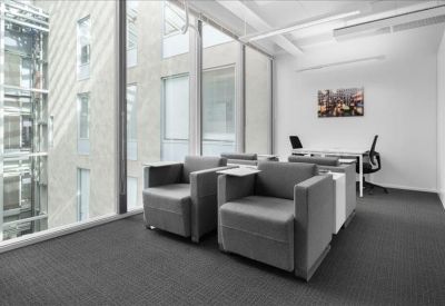Quiet breakout area with grey armchairs next to floor-to-ceiling windows.