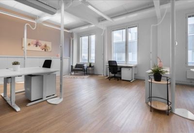 Spacious open-plan workspace with wooden floors, white desks, and large windows.