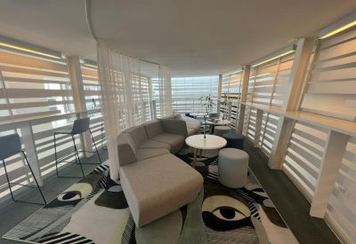 Modern lounge area with curved grey sofa, round tables, and decorative eye-patterned rug.