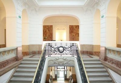Elegant white marble staircase with an ornate black wrought iron railing and grand archways.