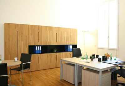 Bright office suite featuring wooden cabinetry, white desks, and black ergonomic chairs.