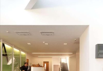 Modern lobby with a white curved reception desk under a skylight.