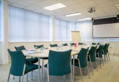 Spacious boardroom at Albion Mills with a long table, green chairs, and a projection screen.