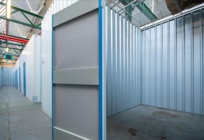 Clean industrial-style storage unit corridor with metallic silver doors and blue trim.