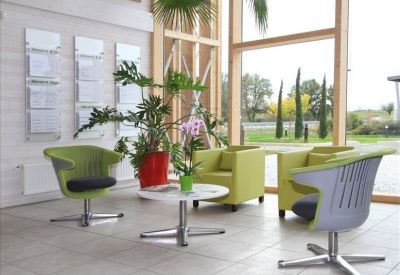 Bright reception area with lime green armchairs, potted plants, and large windows.
