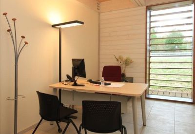 Private office featuring a wooden desk, floor lamp, and a large window with louvres.