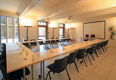 Spacious U-shaped meeting room with black chairs and a projector screen.