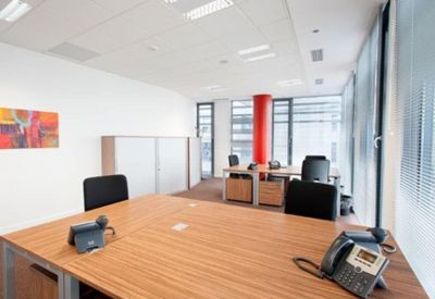 Professional meeting space with a large wooden table, telephone equipment, and abstract art.