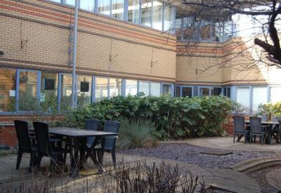 Landscaped outdoor courtyard area with several patio tables and chairs for staff.