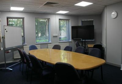 Professional meeting room with a large oval table, blue chairs, and a whiteboard.