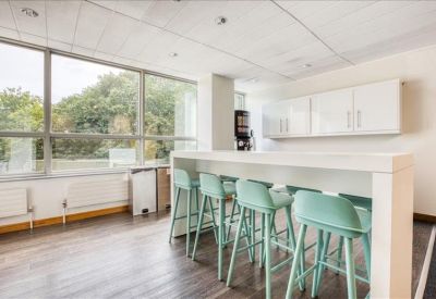 Bright communal kitchen area with a high breakfast bar and stylish teal stools.