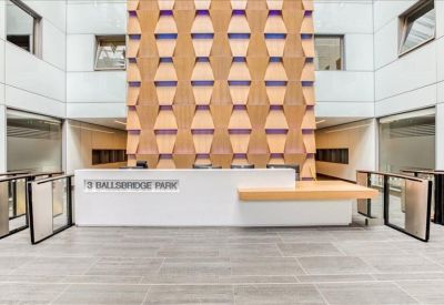 Contemporary reception lobby featuring a white front desk and a geometric wood-panelled feature wall.