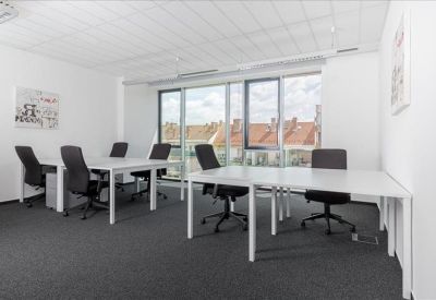 Bright four-person office suite with white desks and windows overlooking neighborhood rooftops.