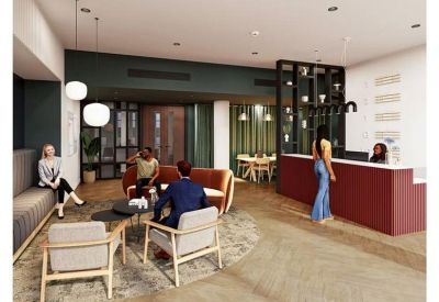 Spacious reception lobby at Ambika House, 9-11 Portland Place with a red front desk and lounge seating.