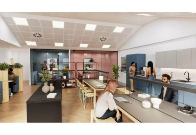 Communal kitchen and dining area with long wooden tables and blue cabinetry.