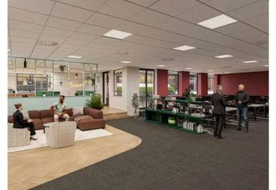 Open-plan office space featuring a mix of lounge seating, workstations, and a dark carpet.