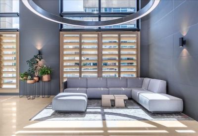 Lounge area with a grey sectional sofa, stylish lighting, and indoor plants.