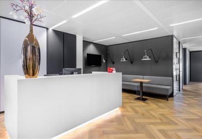 Sleek white reception desk in a modern lobby with chevron wood flooring and a grey feature wall.