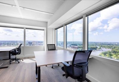 Bright corner office with two desks and expansive windows overlooking the city and water.