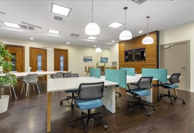 Spacious communal coworking area with long tables, teal privacy screens, and wood accent walls.