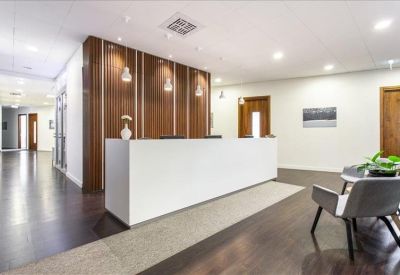 Modern reception area featuring a white desk against a rich wood panelled wall and dark floors.