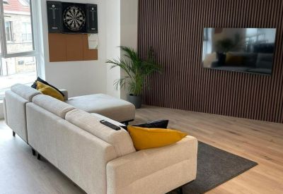 Lounge area with a comfortable beige sofa, wall-mounted TV, and wood-slat feature wall.