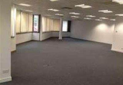 Spacious open-plan office area with grey carpeting and recessed ceiling lighting.