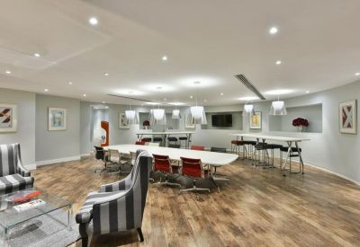 Spacious communal lounge with a long white table and striped armchairs.