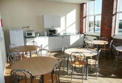 Spacious communal kitchen and dining area with round tables and bright windows.