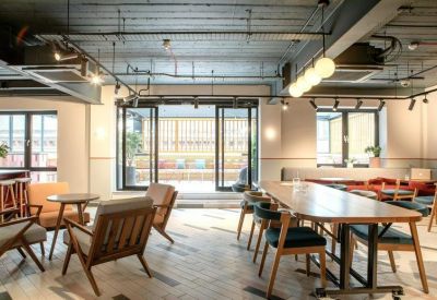 Spacious coworking lounge with a mix of lounge chairs and a long communal table.