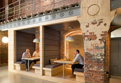 Private breakout booths with built-in seating and tables under an industrial brick arch.