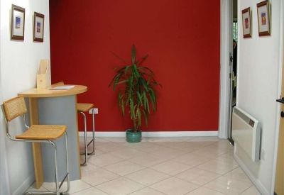 Reception area featuring a vibrant red feature wall, tall plant, and tall bistro table.