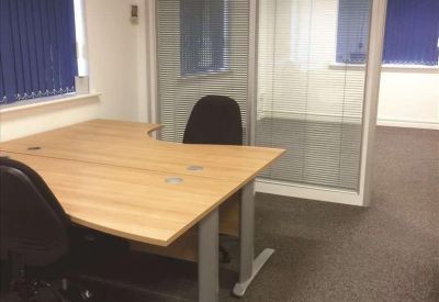 Private office space with a curved wooden desk and glass partitioned walls.