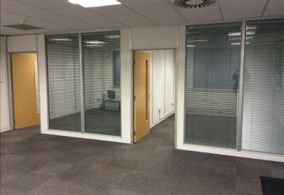Empty office suite with grey carpet and glass walls looking into other rooms.