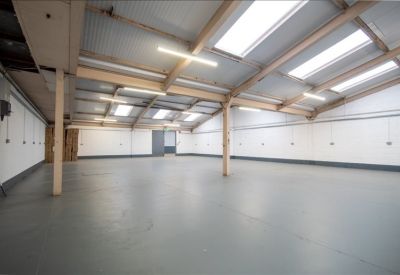 Spacious warehouse interior with skylights and grey flooring.