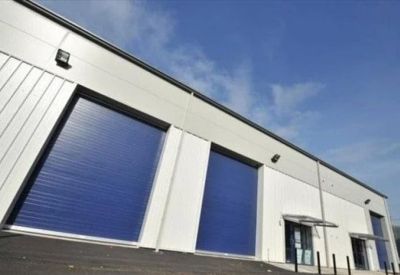Industrial facade with blue roller shutter doors and white cladding.