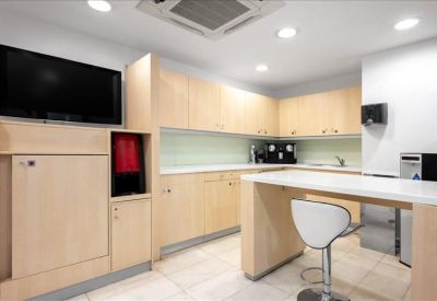 Modern communal kitchen and breakout area with light wood cabinetry and a breakfast bar.