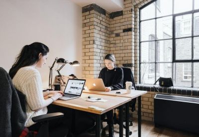 Two-person private office with brick feature wall and large windows.