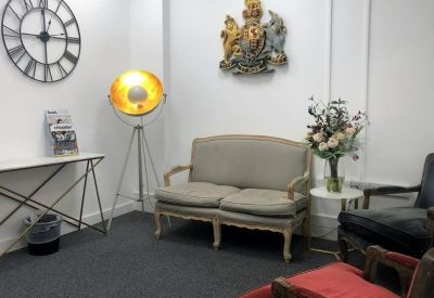 Sophisticated lounge area with a classic grey loveseat, floor lamp, and floral arrangement.