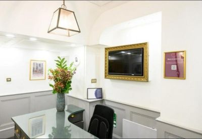 Modern reception desk with a floral arrangement, framed screen, and soft overhead lighting.