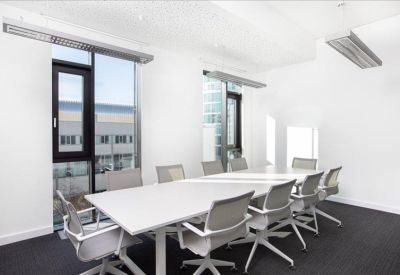 Boardroom with a long white table and grey ergonomic chairs.