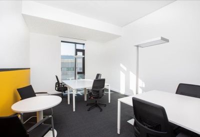 Bright private office with white desks and a yellow feature wall.