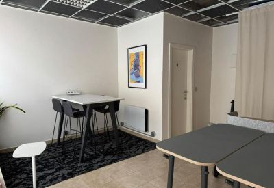 Communal breakout space with high-top tables, modern art, and a dark patterned rug.