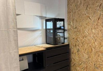 Tech station with a 3D printer on a black storage unit and white acoustic panels.