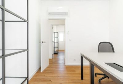 Modern private office with a white desk, grey chair, and air conditioning unit.