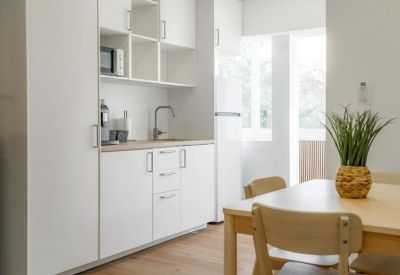 Clean kitchenette with white cabinetry, microwave, and integrated sink.