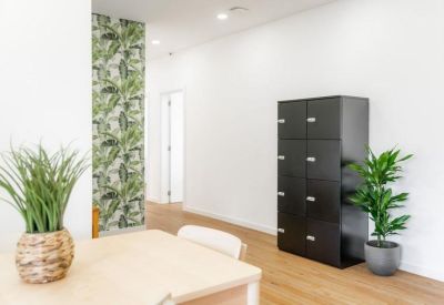 Open space featuring black lockers and a vibrant tropical leaf wallpaper accent.