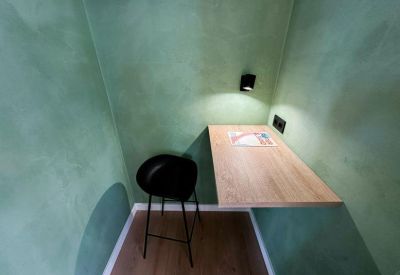 Private phone booth or study nook with green textured walls and a wooden desk.
