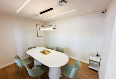 Minimalist meeting room with an oval white table and light green chairs.