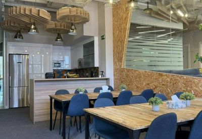 Modern communal kitchen and dining area with blue chairs and natural wood textures.